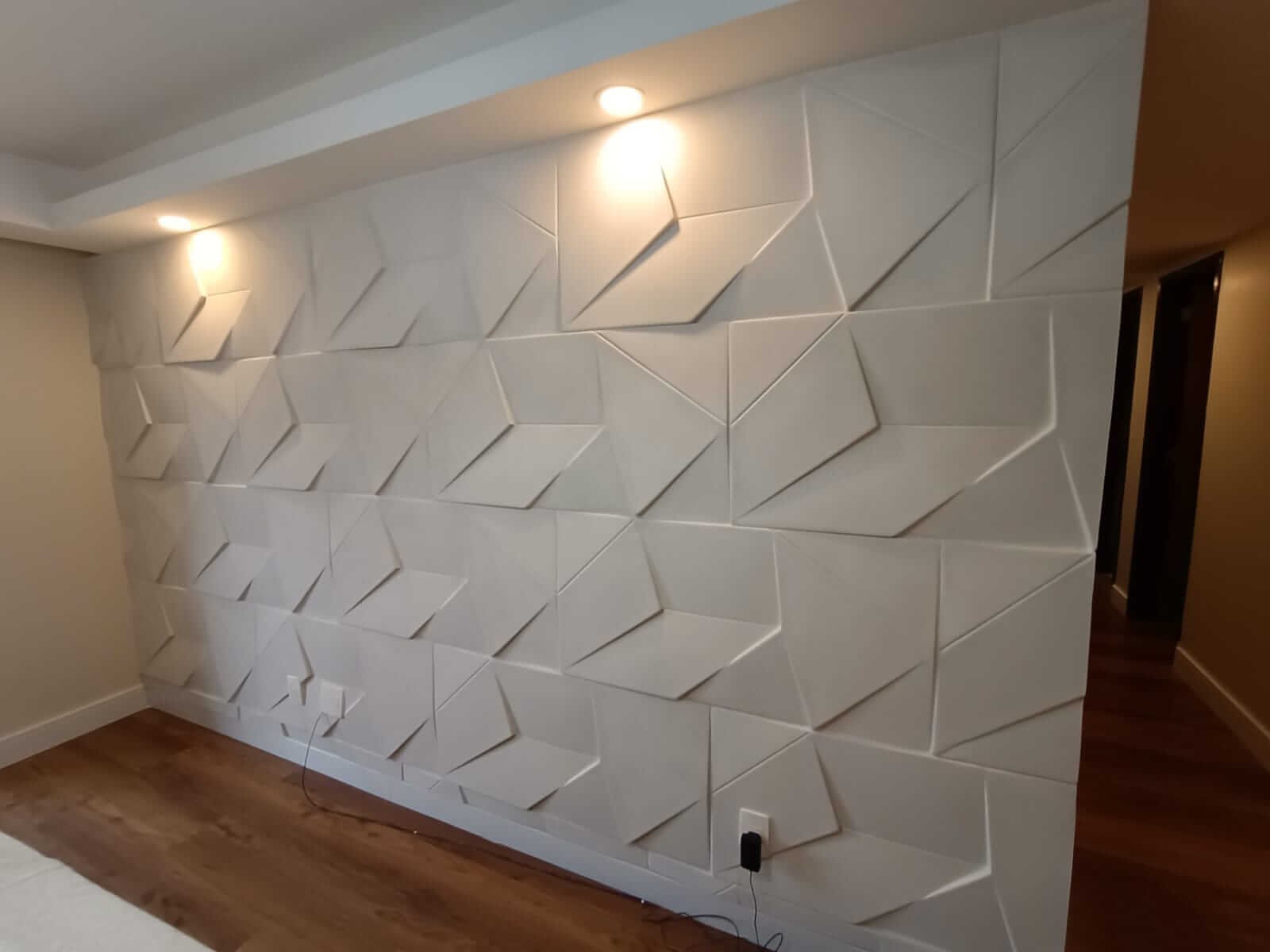 Parede com placas 3D geométricas e iluminação focal